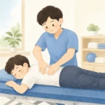 물리치료사가 환자의 허리 부위에 양손을 올려 도수치료를 시행하는 장면, 밝은 치료실 배경