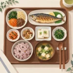 잡곡밥과 나물, 구운 생선, 두부와 견과류가 담긴 한국식 밥상을 위에서 내려다본 장면