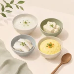 죽과 두부, 흰살생선, 달걀찜이 담긴 작은 그릇들이 식탁에 차려진 모습
