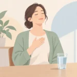 가슴에 손을 얹고 숨을 고르는 사람과 옆에 놓인 물컵