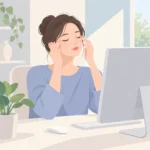 모니터 앞에 앉아 눈을 감은 채 손끝으로 눈가를 가볍게 짚고 있는 사람